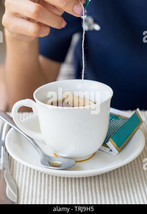 Hand women dipped in white tea cup Stock Photo