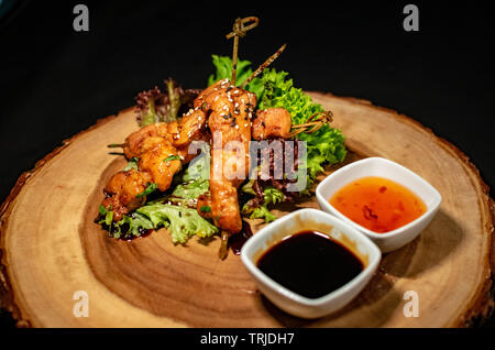 an amazing fresh look for a teriyaki chicken skewer starter dish accompanied by a selection of sauces Stock Photo