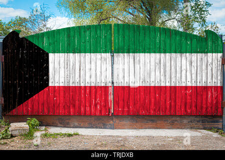 Close-up of the national flag of Kuwait on a wooden gate at the entrance to the closed territory on a summer day. The concept of storage of goods, ent Stock Photo