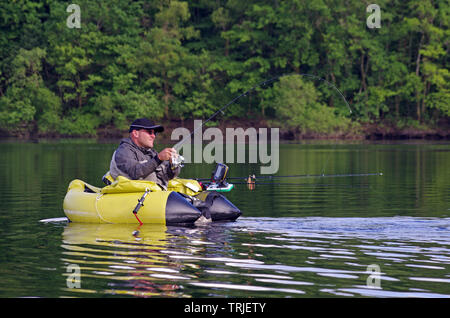 A fisherman fight against a pike. The man is sitting in the fishing inflatable boat and he use flippers to move on the water. He also use a sonar Stock Photo