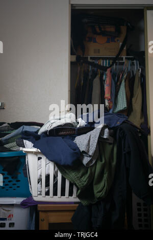 stacks of clothes and laundry with a closet full of clothes Stock Photo