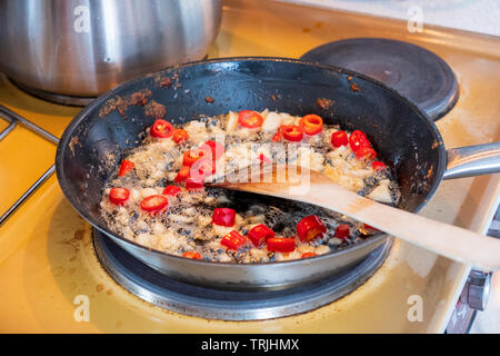 Wooden flipper frying chili with garlic on vegetable oil in pan Stock Photo