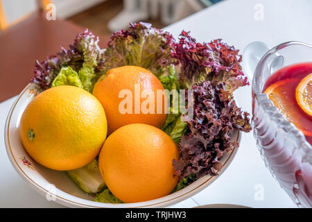 Mandarin oranges with lettuce in bowl on white table Stock Photo