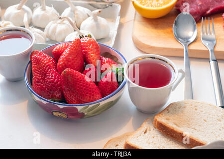 Strawberry fruit with tea in ceramic crockery on dining table for weekend Stock Photo