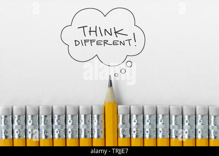 Pencil tip standing out from croud of pencil rubber erasers with Think different word on thought bubble
