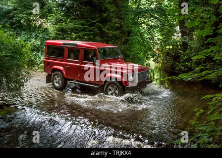 Red Land Rover Defender 110 4WD car navigating a Ford on a Green Lane track, North Yorkshire Moors, UK. Stock Photo