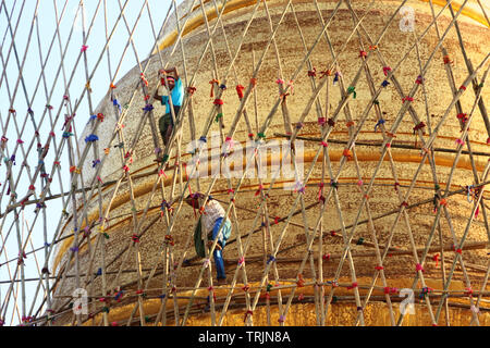 This workers are buildings a bamboo scaffolding to make repair works at a stupa. Photo was taken near Mandalay, Myanmar. Stock Photo