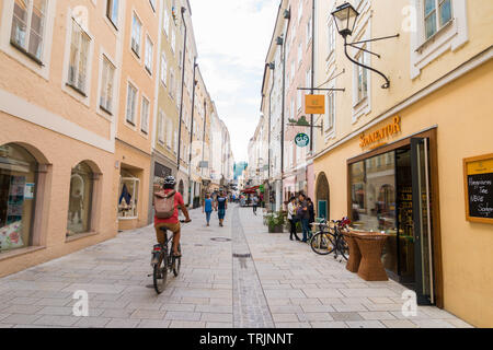Salzburg, Austria - September 13, 2018: People walking and riding bicycle on Linzergasse - popular pedestrian shopping street on the right side of Sal Stock Photo