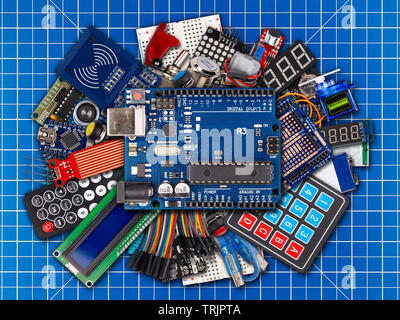 collage of microcontroller board display sensor button switches cable wire accessories and equipment on blue cutting matte workplace electronics conce Stock Photo