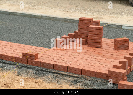 Laying red tiles on the sidewalk outdoors. Renovating paving in the street, construction, urban development Stock Photo