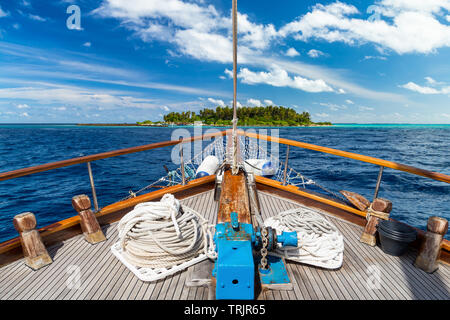 luxury sailing boat yacht in front of tropical paradise maldives island resort with coral reef and turquoise blue ocean water tourism background Stock Photo