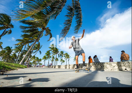MIAMI - DECEMBER 27, 2017: A young man rides his skateboard along the beachfront boardwalk promenade at Lummus Park in South Beach. Stock Photo