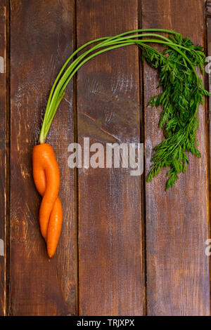 Funny ugly carrot on wooden background. Image with copy space, top view. Stock Photo