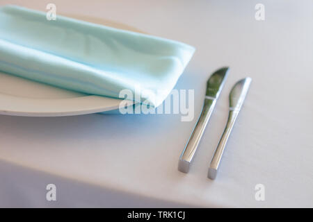 White plate with a turquoise napkin, metal fork and knife, table setting wedding Stock Photo