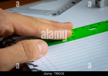 Hand holding green rule on a notebook close up Stock Photo