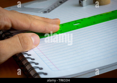 Hand holding green rule on a notebook Stock Photo