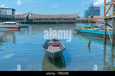 SEMPORNA SABAH - MAY10 2-17;  tourist small boat harbour dinghy tied up near pier with famous Dragon Inn resort buildt over water in background. Stock Photo