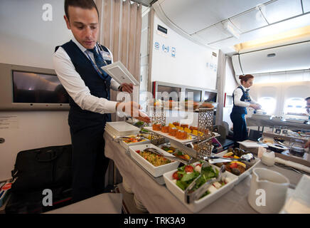 In flight crew serving gourmet dinner in business class section of Turkish airlines flight from Istanbul to Los Angeles, Stock Photo