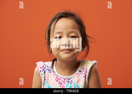 Close-up bright portrait of asian girl isolated on orange color Stock Photo