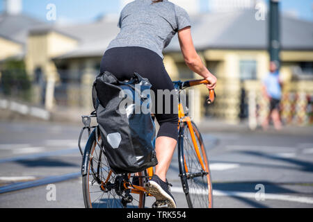 A woman cyclist in sportswear crosses the tram rails on a bicycle, preferring an active way of relaxation, helping her to keep herself in good shape, Stock Photo