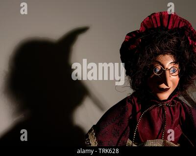 Puppet of a witch casting shadow on wall. Stock Photo