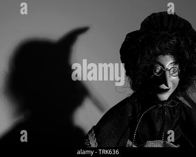 Puppet of a witch casting shadow on wall. Stock Photo