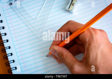 Hand holding a pen wih a rule on a notebook Stock Photo