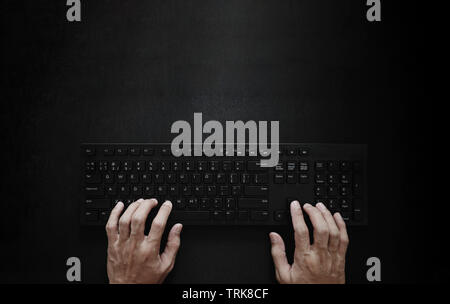 Top view, Hand typing computer keyboard on black background Stock Photo