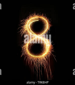 burning sparkler stick and writing sparkling text . number eight isolated on black background Stock Photo