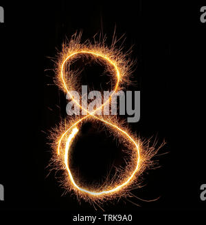 burning sparkler stick and writing sparkling text . number eight isolated on black background