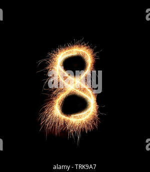 burning sparkler stick and writing sparkling text . number eight isolated on black background Stock Photo