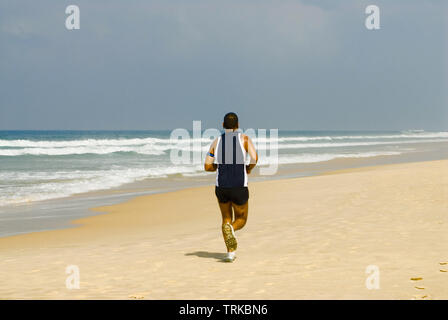Man running along the beach. Rear view Stock Photo