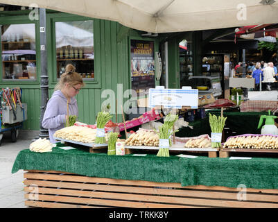 May 2019 - A young, caucasian blonde female sells white asparagus from a stand in the Victuals Market in Munich, Germany Stock Photo