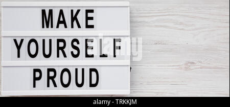 'Make yourself proud' on a lightbox on a white wooden background, top view. Flat lay, overhead, from above. Copy space. Stock Photo
