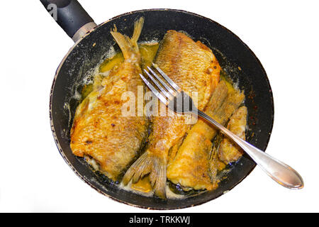 The photo of the whole fried fish without head on the frying-pan or skillet with a fork on it Stock Photo
