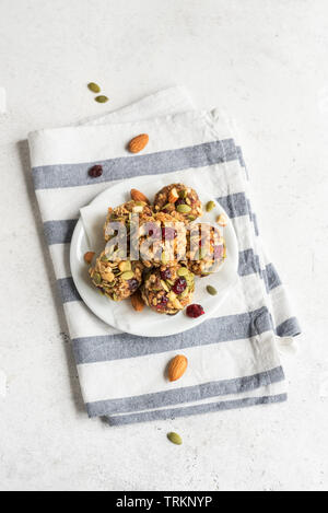 Energy granola bites with nuts, seeds, dry cranberries and honey - vegan vegetarian raw organic snack granola bites on white background, copy space. Stock Photo