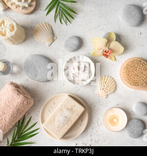 Spa concept, flat lay on white stone background, palm leaves, flower, candle and zen like grey stones, top view. Stock Photo