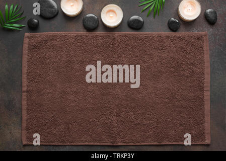 Spa concept on dark background, palm leaves, candles and zen like black stones, top view, copy space. Spa composition with towel. Stock Photo