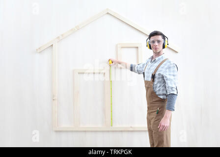 house construction renovation concept handyman carpenter worker man with meter  measure and show the model of a wooden house, custom solutions Stock Photo