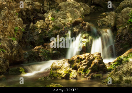 Small waterfall and stream of water among rocks and boulders in summer (Seven Springs, Rhodes, Greece) Stock Photo