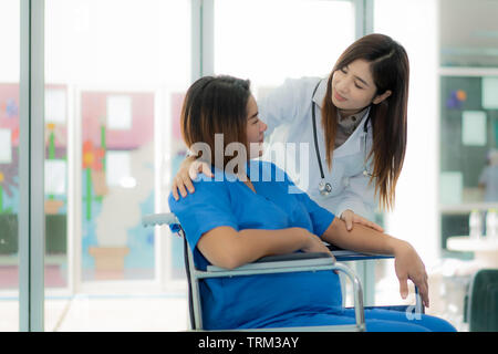Friendly Asian female medicine doctor hands holding pregnant woman's hand for encouragement, empathy, cheering and support while medical examination. Stock Photo