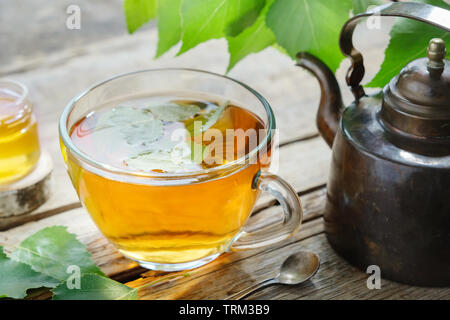 Birch leaves, healthy herbal tea cup, honey jar and vintage copper tea kettle. Stock Photo