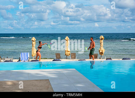 A tourists couple play a racket game by the swimming pool at Breakas Resort, Port Vila, Efate Island, Vanuatu, Melanesia Stock Photo