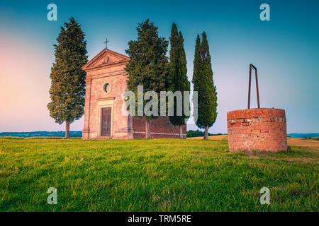 Popular photography and touristic location in Tuscany, amazing Vitaleta chapel and old stone water well at colorful sunset, Pienza, Tuscany, Italy, Eu Stock Photo