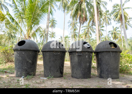 Four plastic dumpsters are on the street near tropical beach on the island of Koh Phangan, Thailand Stock Photo