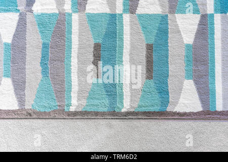 Background graphic, top view of a geometric rug with blue and grey color patterns, on top of a beige carpet, as a design element in home decor. Stock Photo
