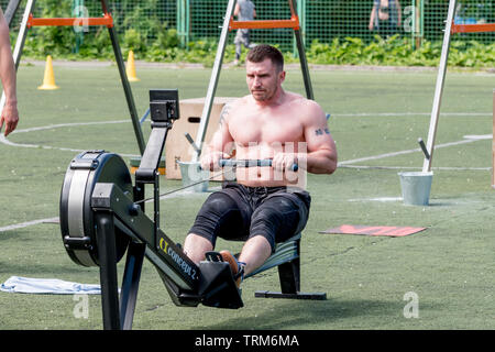 Russia, Vladivostok, 06/01/2019. A strong sportsman does physical exercises on rowing machine. Workout crossfit sports, active sports. Stock Photo