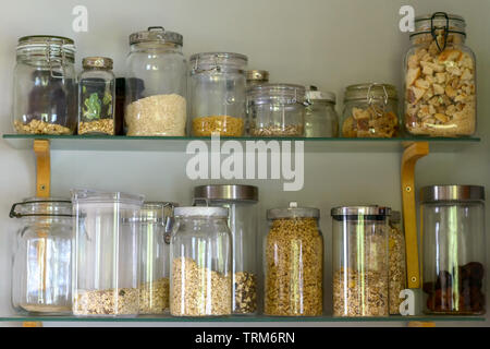 Pantry or kitchen shelf with assorted dried food ingredients in a variety of different glass storage jars in a close up full frame view Stock Photo