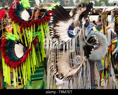 Two Native American fancy dancers waiting to dance at a pow wow at Crow Fair in Montana. Photographed from behind. Stock Photo
