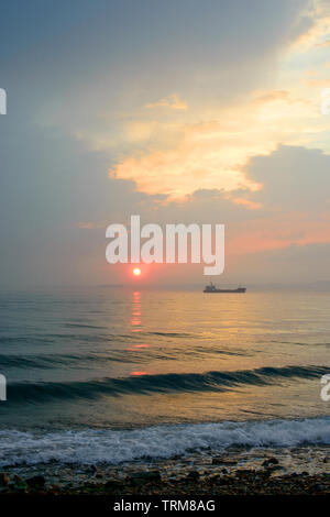 Beautiful cloudy sunset and sea landscape. Pink and gold colored sky in the evening. Stock Photo